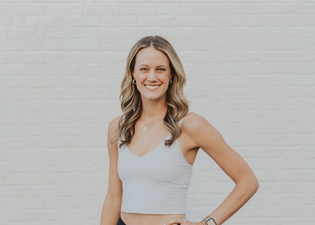 A woman standing in front of a white wall.