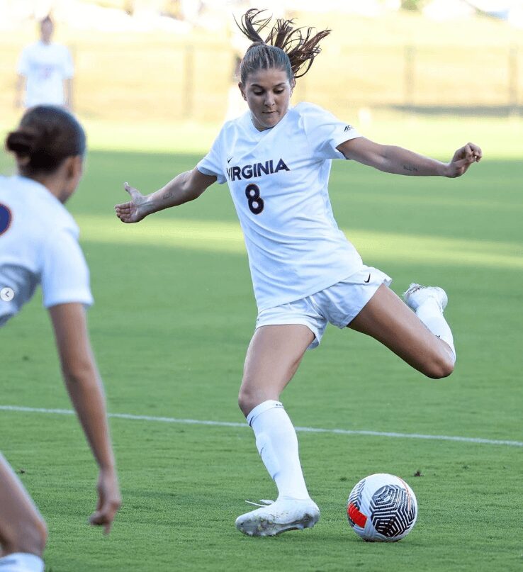 A woman kicking around the soccer ball on a field.