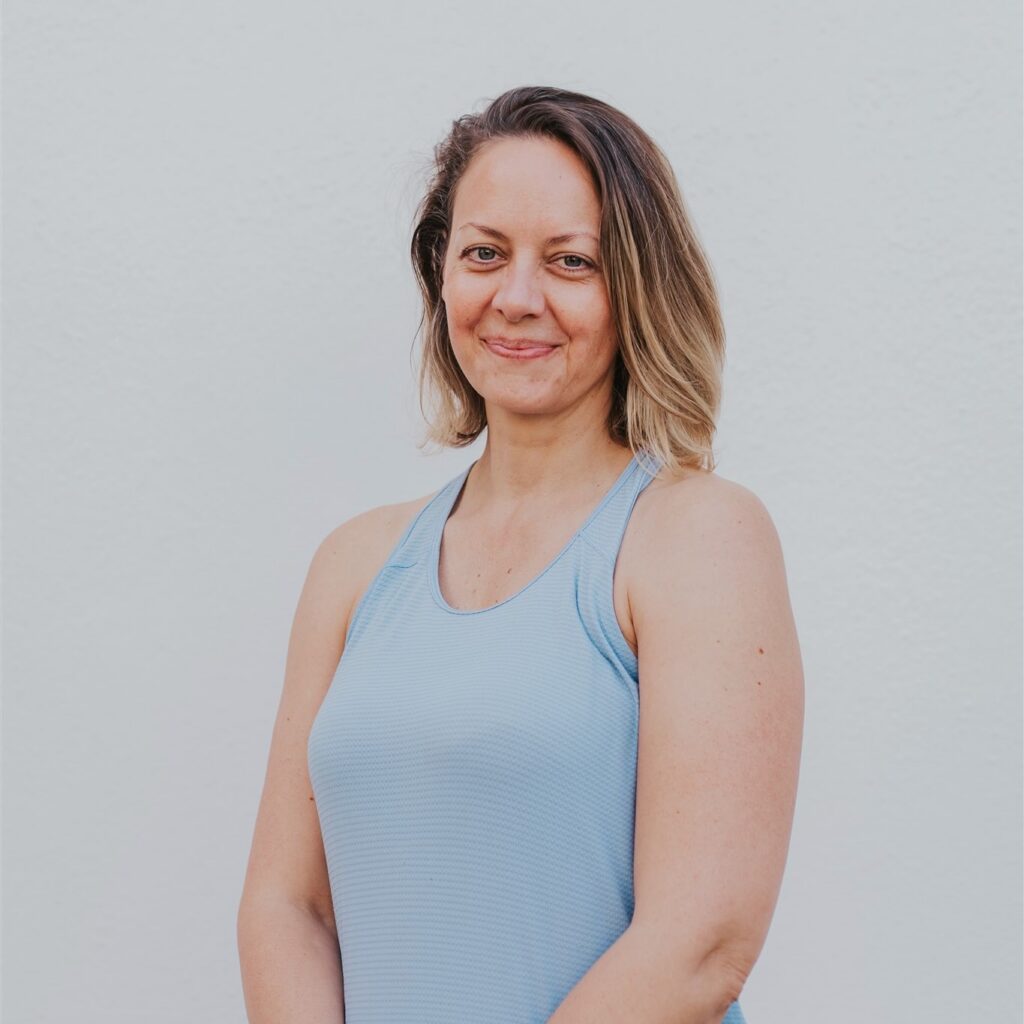 A woman standing in front of a white wall.