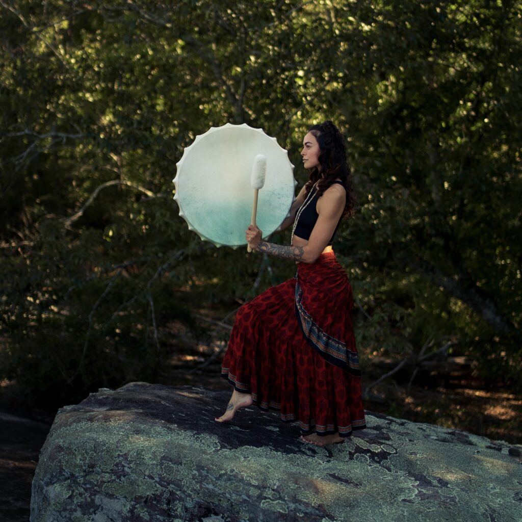 A woman holding an umbrella while standing on top of a rock.