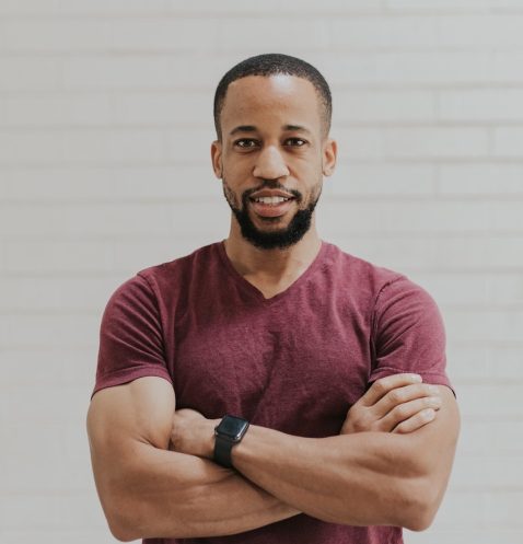 A man with his arms crossed standing in front of a wall.