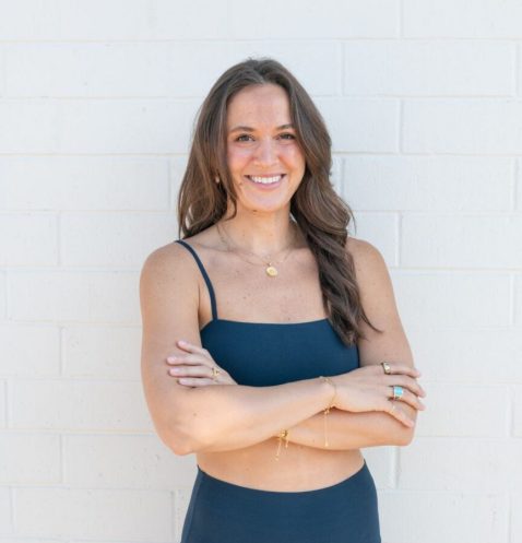 Woman in navy sportswear smiling with crossed arms
