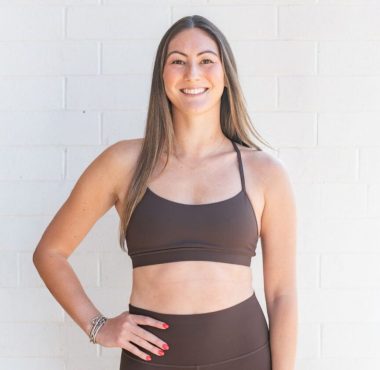Smiling woman in brown activewear against white wall
