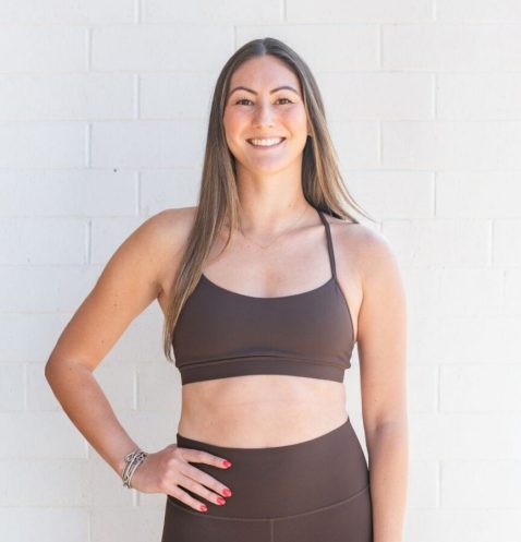 Smiling woman in brown activewear against white wall