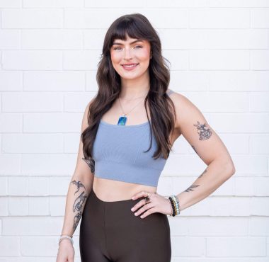 Smiling woman with tattoos against white background.