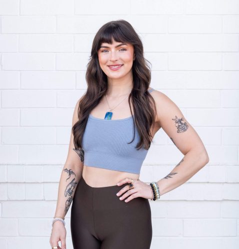 Smiling woman with tattoos against white background.