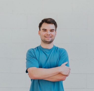Man in blue shirt standing, arms crossed.