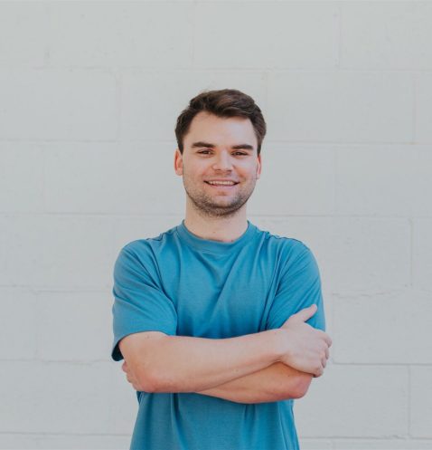 Man in blue shirt standing, arms crossed.