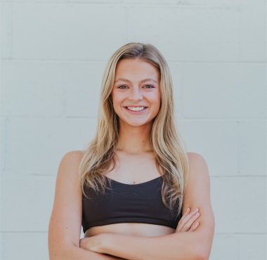 Smiling woman in athletic wear, arms crossed.