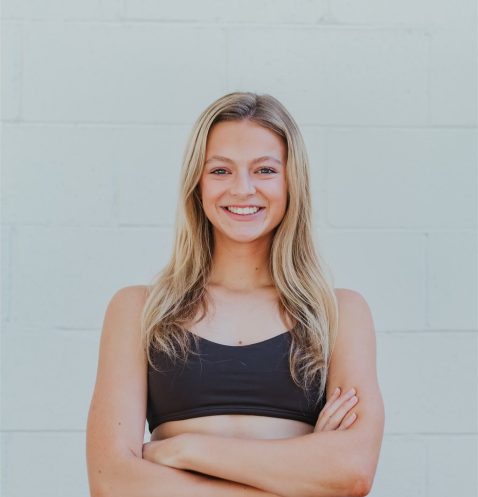 Smiling woman in athletic wear, arms crossed.