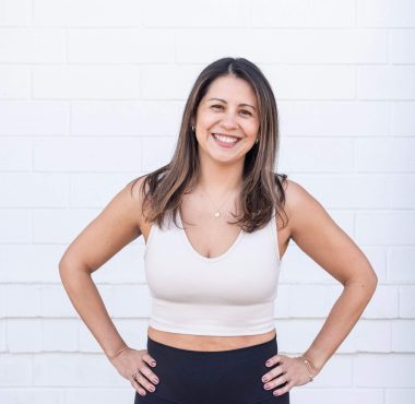 Smiling woman in sportswear against brick wall.