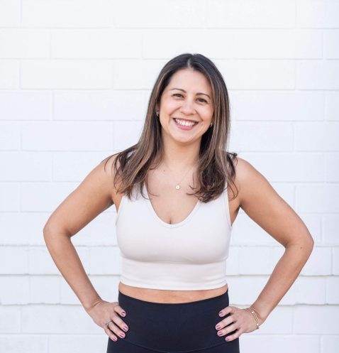 Smiling woman in sportswear against brick wall.