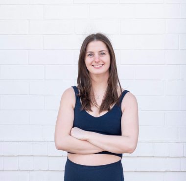 Woman smiling in front of white brick wall.