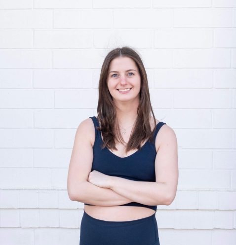 Woman smiling in front of white brick wall.