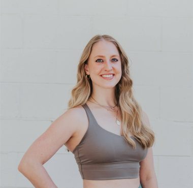 Smiling woman in activewear against white wall.