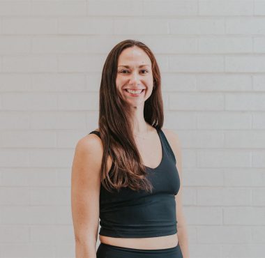 Smiling woman in black fitness attire.