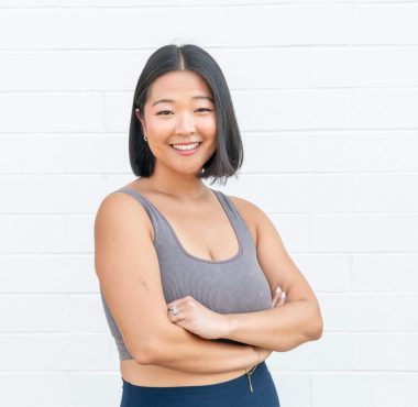 Smiling woman standing against white brick wall.