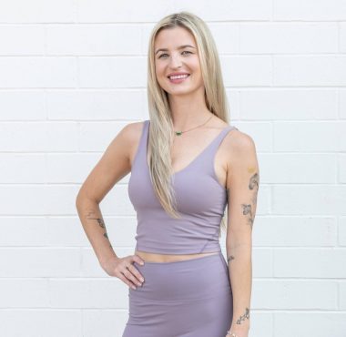 Woman in lavender workout outfit, smiling confidently.
