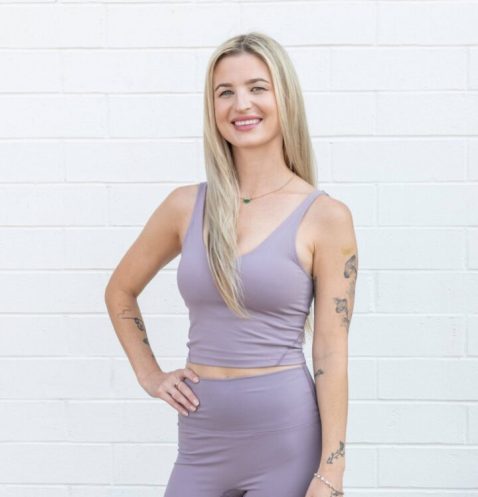 Woman in lavender workout outfit, smiling confidently.