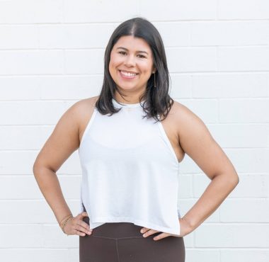 Smiling woman in casual outfit against wall.