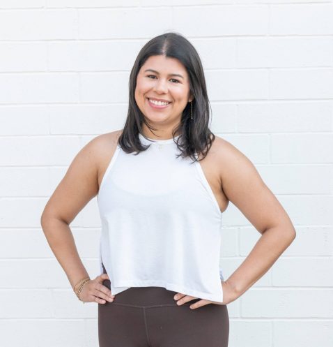 Smiling woman in casual outfit against wall.