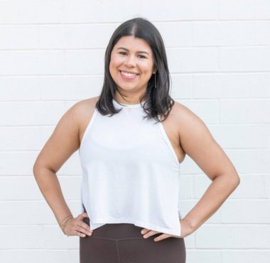 Smiling woman in casual outfit against wall.