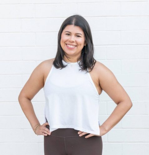 Smiling woman in casual outfit against wall.