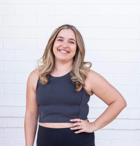 Smiling woman standing against white brick wall.