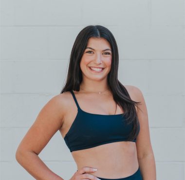Smiling woman in athletic wear posing confidently.