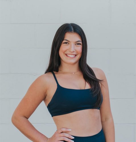 Smiling woman in athletic wear posing confidently.