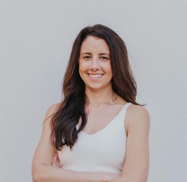 A woman standing in front of a white wall.