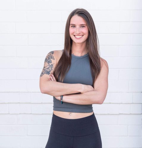 Woman smiling with arms crossed, white background.