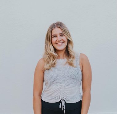 A woman standing in front of a white wall.