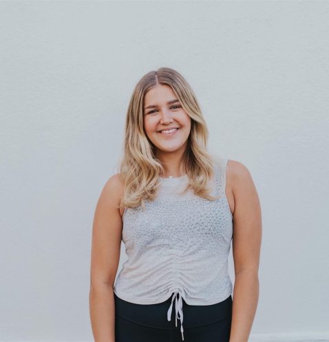 A woman standing in front of a white wall.