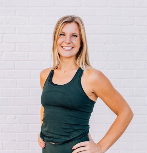 Smiling woman in activewear against white brick.