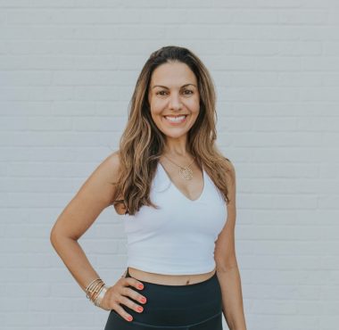 A woman standing in front of a white wall.