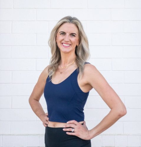 Smiling woman in athletic attire against wall.