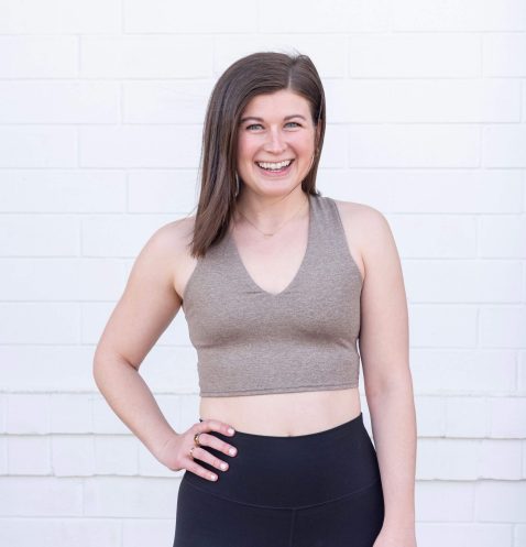 Smiling woman in workout attire, white background.