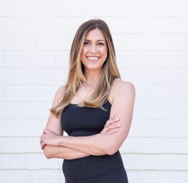 Smiling woman in black outfit, white background.