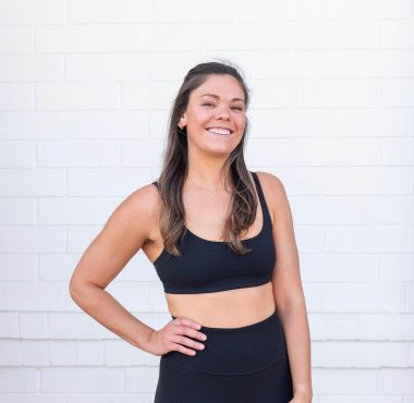 Smiling woman in black workout attire.