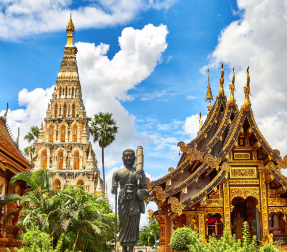 Ornate temple with statue and pagoda tower.