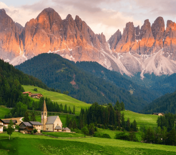 Mountain village with dramatic peaks at sunset.