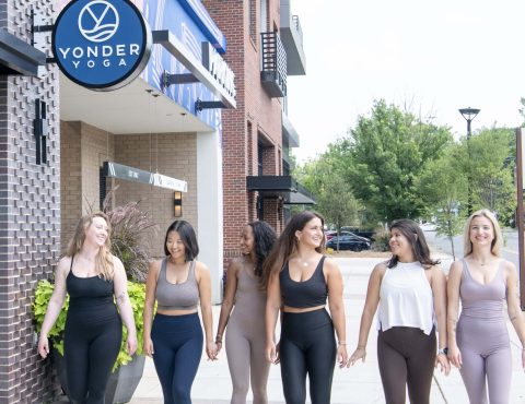 Women walking outside yoga studio, smiling together.