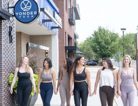 Women walking outside yoga studio, smiling together.