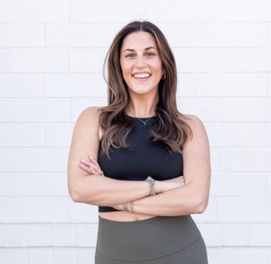 Smiling woman in black top, white background.