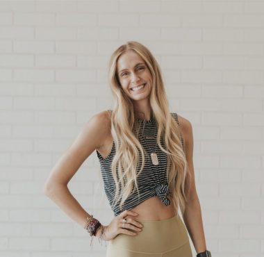 Smiling woman posing against white brick wall.