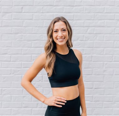 A woman standing in front of a white brick wall.