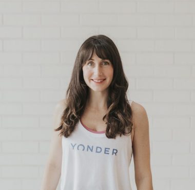 Woman smiling in front of white brick wall.