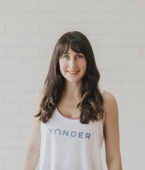 Woman smiling in front of white brick wall.
