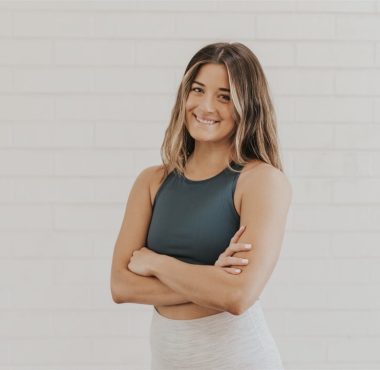 Smiling woman in athletic wear, arms crossed.